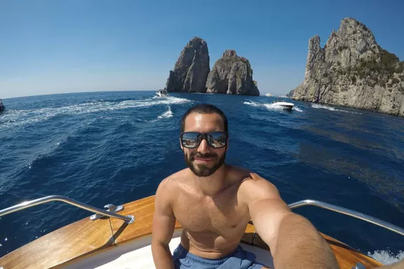 Turista tirando uma selfie em frente as Rochas de Faraglioni, na Ilha de Capri